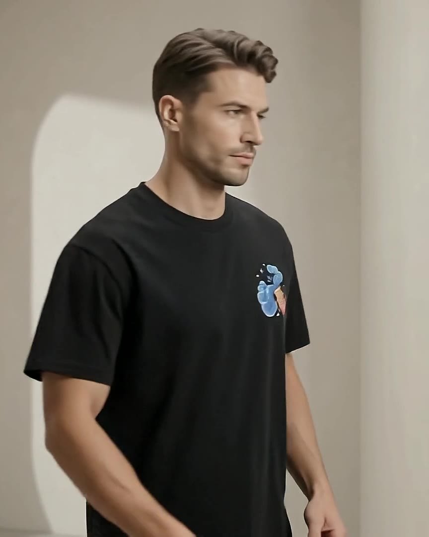 A model in the black Aquadoir tee with the Aquarius print, standing in soft daylight against a warm arched wall